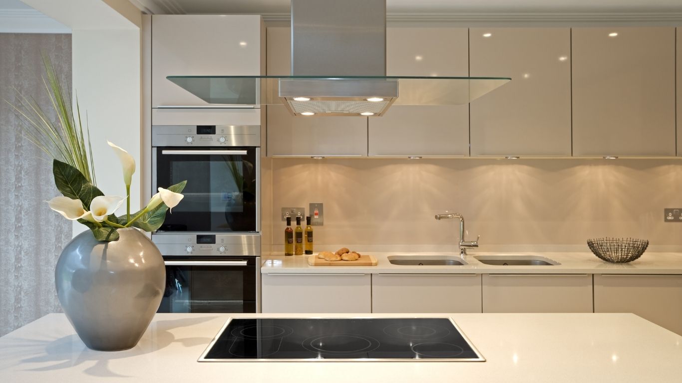 KITCHEN RENOVATION (4) Modern kitchen with beige cupboards, a built-in oven, electric hob, double sink, decorative vase with flowers, and a bowl on the worktop.