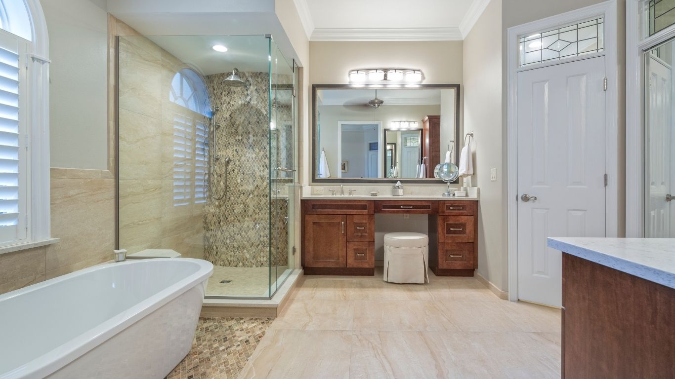 The Handyman Services and Renovations Barrie (2) Modern bathroom with a freestanding bath, glass-enclosed shower, wooden vanity with double basins, large mirror, and neutral tiled flooring. - The Handyman Services Barrie