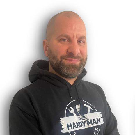 A man with a shaved head and beard wears a black "The Handy Man" hoodie, standing against a plain white background.
